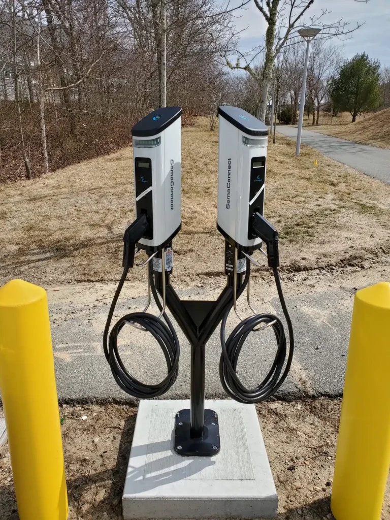 Electric vehicle charging station with dual SemaConnect chargers, set in a natural outdoor environment, showcasing clean energy solutions for businesses in Massachusetts.