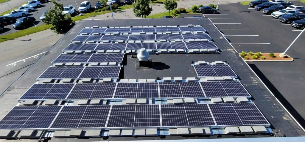Solar panel installation on Audi dealership roof in Cape Cod, MA, showcasing a large array of solar panels contributing to clean energy solutions for commercial businesses.