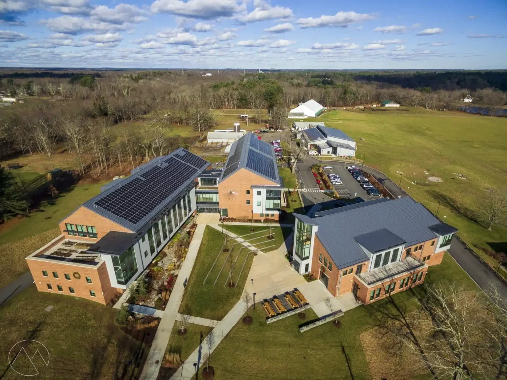 Aerial view of a commercial building with solar panels on the roof, surrounded by landscaped grounds and parking area, showcasing BD Electrical Services' solar power installation expertise.