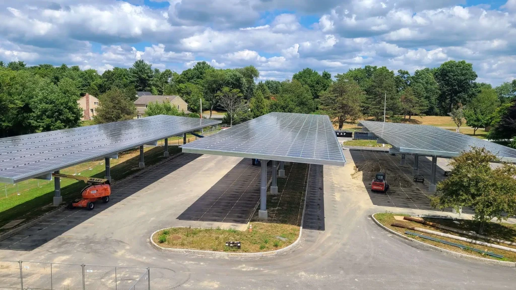 Solar canopy installation at Brophy Elementary School showcasing multiple rows of solar panels, surrounded by greenery and a partially paved area, emphasizing clean energy solutions for educational institutions.