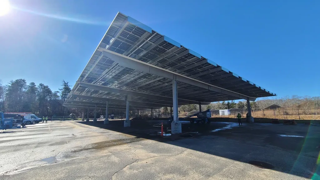 Cape Cod Community College solar canopy installation, showcasing large solar panels on a structured framework in a commercial setting, emphasizing clean energy solutions.