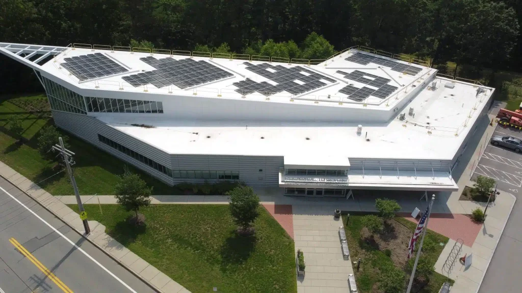Mcauliffe Library in Middleborough, Massachusetts, featuring a modern design with solar panels installed on the roof, surrounded by greenery and pathways, illustrating BD Electrical Services' commercial solar power projects.